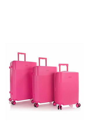 Ensemble de trois valises rigides rose vif avec poignées télescopiques et quatre roues doubles pivotantes, présentées par taille décroissante.