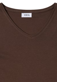 Braunes V-Ausschnitt-T-Shirt aus glattem Baumwollmaterial. Das Etikett zeigt den Markennamen "CECIL". Einfaches Design mit weicher Textur.