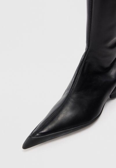 Must musta ankle boot terava varba ja kitsene kand, millel on sile tekstuur ja minimaalne õmblusdetail külgedel.