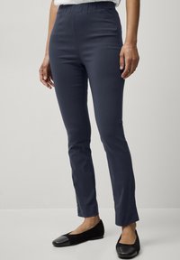 Pantaloni elasticizzati blu navy con vita elasticizzata, vestibilità slim e texture liscia. Abbinati a ballerine nere con punta tonda e accenti a contrasto.