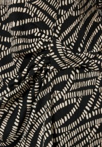 Tejido negro con una superficie texturizada que presenta un patrón abstracto en blanco de líneas y formas, creando un contraste visual dinámico.
