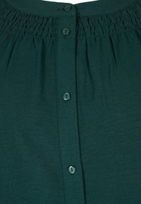 Blusa verde scuro con scollatura arricciata, chiusura frontale con bottoni coordinati e un tessuto morbido e strutturato.