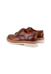 Chaussures habillées en cuir marron avec des détails perforés, bout rond et semelle basse à plateforme avec une finition naturelle semblable au bois.