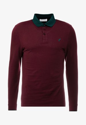 Langarm-Polohemd in tiefrot mit einem dunkelgrünen Kragen, dreiknopfiger Blende und einem kleinen Vogel-Logo auf der Brust. Glatte Textur.