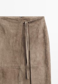 Taupe suede skirt featuring a high waist, front tie closure, and panel stitching. Soft texture with a smooth finish.