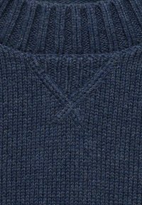 Námořnický pletený svetr se zdobným ribkováním, vysokým límcem a V-tyčeným švem na krku, vyrobený z měkkého, zkrouceného vlákna.