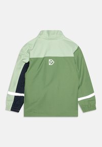 Veste verte au design bicolore avec une partie supérieure vert clair et une partie inférieure vert foncé. Comprend des bandes réfléchissantes blanches et un logo.