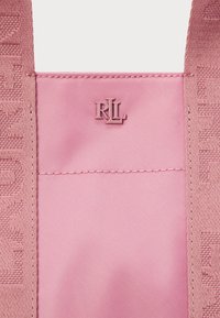 Różowa torba materiałowa z wytłaczanym wzorem. Ma małe, wystające logo „RL” w dopasowanym kolorze, podkreślające jej gładką teksturę.