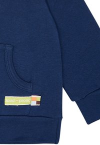 Felpa in cotone blu navy con tasca frontale, polsini a coste e un'etichetta che mostra "loud + proud" con accenti verdi, marroni e arancioni.