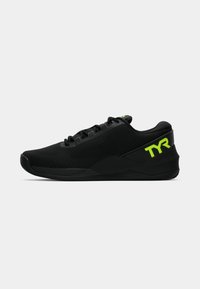 Zapatillas deportivas negras con parte superior texturizada, cordones y acentos en verde brillante. Presentan un diseño de punta redondeada y una suela gruesa.