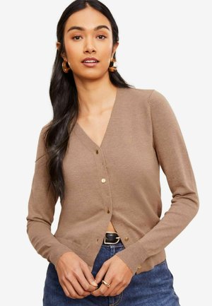 Cardigan en tricot marron avec un col en V, des boutons à l'avant et des manches longues, présentant un design ajusté et une texture subtile. Associé à un denim.