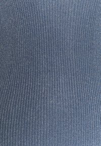 Gros plan sur un tissu tricoté bleu à côtes avec des lignes texturées verticales et de subtils fils métalliques argentés tissés partout.
