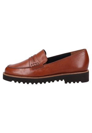 Mocassin en cuir marron avec coutures apparentes, bout arrondi et semelle en caoutchouc noire texturée. Design minimaliste sans quincaillerie visible.