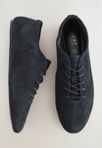 Scarpe in suede blu scuro con punta appuntita, caratterizzate da un design con lacci e dettagli di cucitura sottili sui lati. Suola resistente.