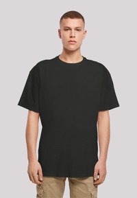 Juodas medvilnės t-shirt su apvalia iškirpte ir trumpomis rankovėmis, pasižymi laisvu fasonu ir glotnia tekstūra, be matomų raštų ar grafikų.