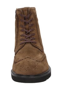 Stivale alla caviglia in suede marrone con chiusura a lacci, dettagli decorativi brogue e suola in gomma. Presenta una cerniera laterale per una facile calzata.
