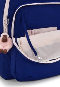 Marineblauwe nylon rugzak met een roze rits en voering. Voorzien van een knuffelzachte roze gorilla sleutelhanger en een voorvak met organisatievakken.
