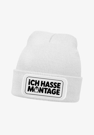 Weißer Strickmütze mit umgeschlagenem Bündchen, versehen mit einem rechteckigen Aufnäher mit dem Text „¡CH HASSE MONTAGE!“ und einer schwarzen Cartoonfigur.