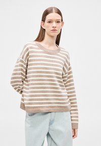 Beežide ja kreemjate triipudega džempr, kerge kampsun koos soonikkoega ümarkaeluse ja mansettidega varrukatega, kombineeritud helesiniste teksadega.