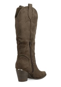 Bota alta hasta la rodilla de ante marrón con punta ligeramente puntiaguda, cremallera lateral y tacón de madera cónico. Presenta un detalle superior con costuras.