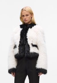 Faux fur jacket featuring a cropped design with black and white coloration, long sleeves, and a textured, fluffy finish.