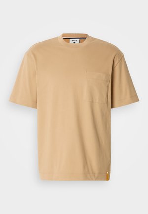 Beige kortærmet t-shirt lavet af bomuld, med rund hals og en brystlomme. Inkluderer et lille orange label på kanten.