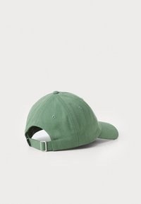 Green cotton baseball cap with a curved brim. Features a fabric strap with a metal buckle at the back and ventilation eyelets.