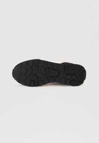 Black rubber shoe sole with textured grip patterns, featuring circular and rectangular protrusions; prominently displays the Fila logo.