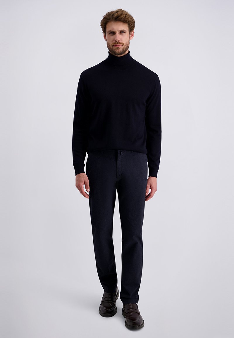 Czarny sweter z golfem, dopasowane ciemne spodnie i ciemne buty wsuwane. Minimalistyczny design o gładkiej teksturze i stonowanych kolorach.