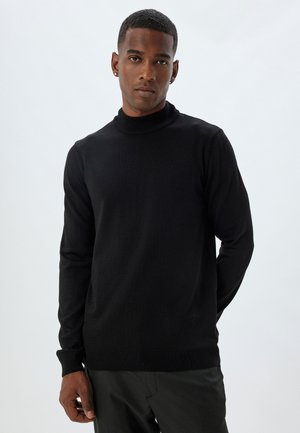 Suéter negro de cuello alto, hecho de un material de punto suave, con mangas largas, diseño ajustado y acentos de canalé en el cuello y el dobladillo.