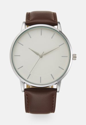 Brunt läderrem klocka med en bezel i silver rostfritt stål, vit urtavla, minimalistiska silvertimmarkörer och smala visare.