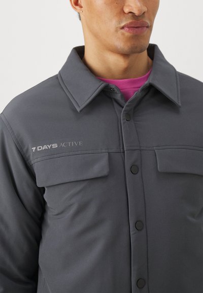 Gray jacket with a buttoned front, two chest pockets, and '7 DAYS ACTIVE' logo. Features a classic collar and smooth fabric texture.