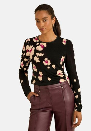 Black long-sleeve top with a floral pattern in pink and cream tones. Features a round neckline and fitted design, paired with burgundy pants.