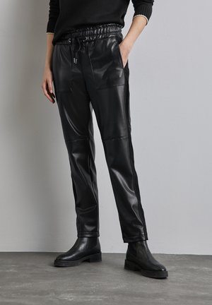Schwarze Lederhosen mit elastischem Bund, Kordelzug und Seitentaschen; hat ein schlankes Design mit glatter Textur.