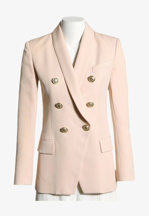 Blazer cruzado rosa claro con seis botones dorados decorativos, cuello con muesca en la solapa y dos bolsillos delanteros con solapa, mostrado en un maniquí.