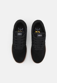 Black suede sneakers with black laces and gum rubber outsole. Features a small "JOSLIN" label on the tongue and a colorful insole design.