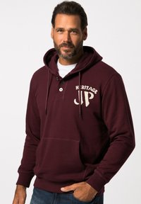 Felpa bordeaux con tasca frontale, bottoni e logo "HERITAGE JP" in crema. Presenta cordini e polsini a coste. Tessuto morbido.