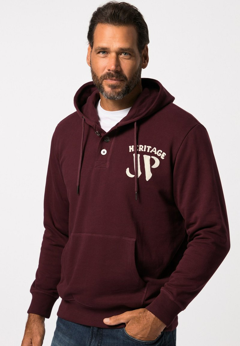 Felpa bordeaux con tasca frontale, bottoni e logo "HERITAGE JP" in crema. Presenta cordini e polsini a coste. Tessuto morbido.