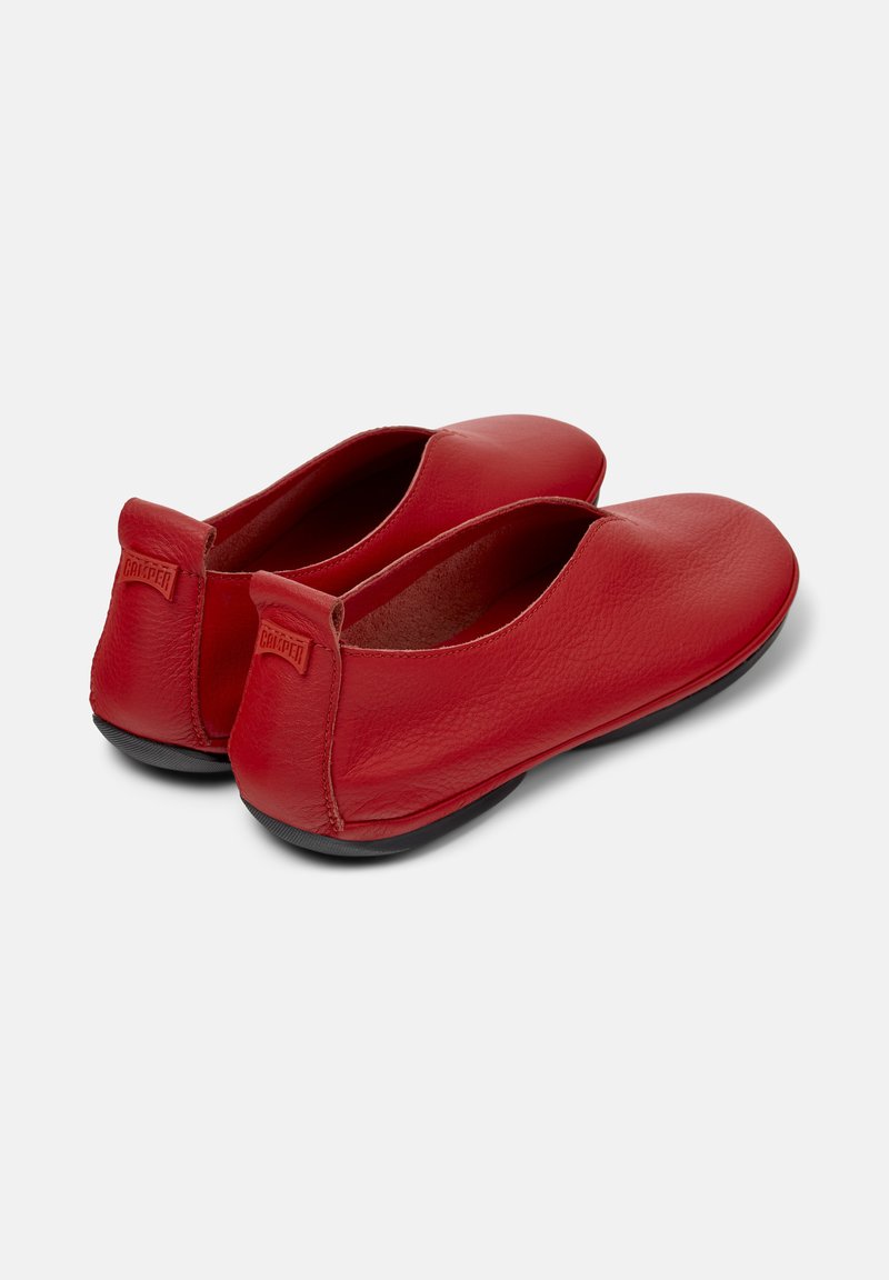 Red leather ballet flats with a soft texture and minimalistic design, featuring a black sole and small brand logo on the heel.