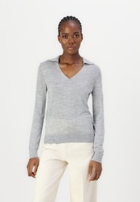 Grauer Pullover mit langen Ärmeln, V-Ausschnitt und Kragen. Leichtes Strickmaterial mit subtiler Textur, kombiniert mit creamfarbenen, weiten Hosen.