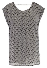 Blouse sans manches noir et blanc avec motif en zigzag et encolure arrondie, tissu léger et coupe ample.