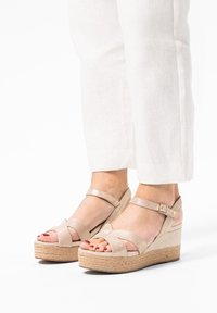 Beige wedge sandalen met gespsluiting en enkelbandje. Lichtjes gestructureerd oppervlak en jute-wikkel middenzool. Blootgestelde tenen met gepolijste nagels.