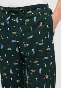 Pantaloni de pijama verzi închise cu un model jucăuș inspirat de golf, ce include crosse de golf, steaguri și mingi în diverse culori. Talie elastică cu șnur.