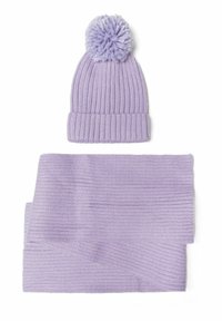 Bonnet en tricot violet avec un pompon duveteux sur le dessus et une écharpe côtelée assortie. Les deux articles présentent une texture douce et une couleur uniforme.