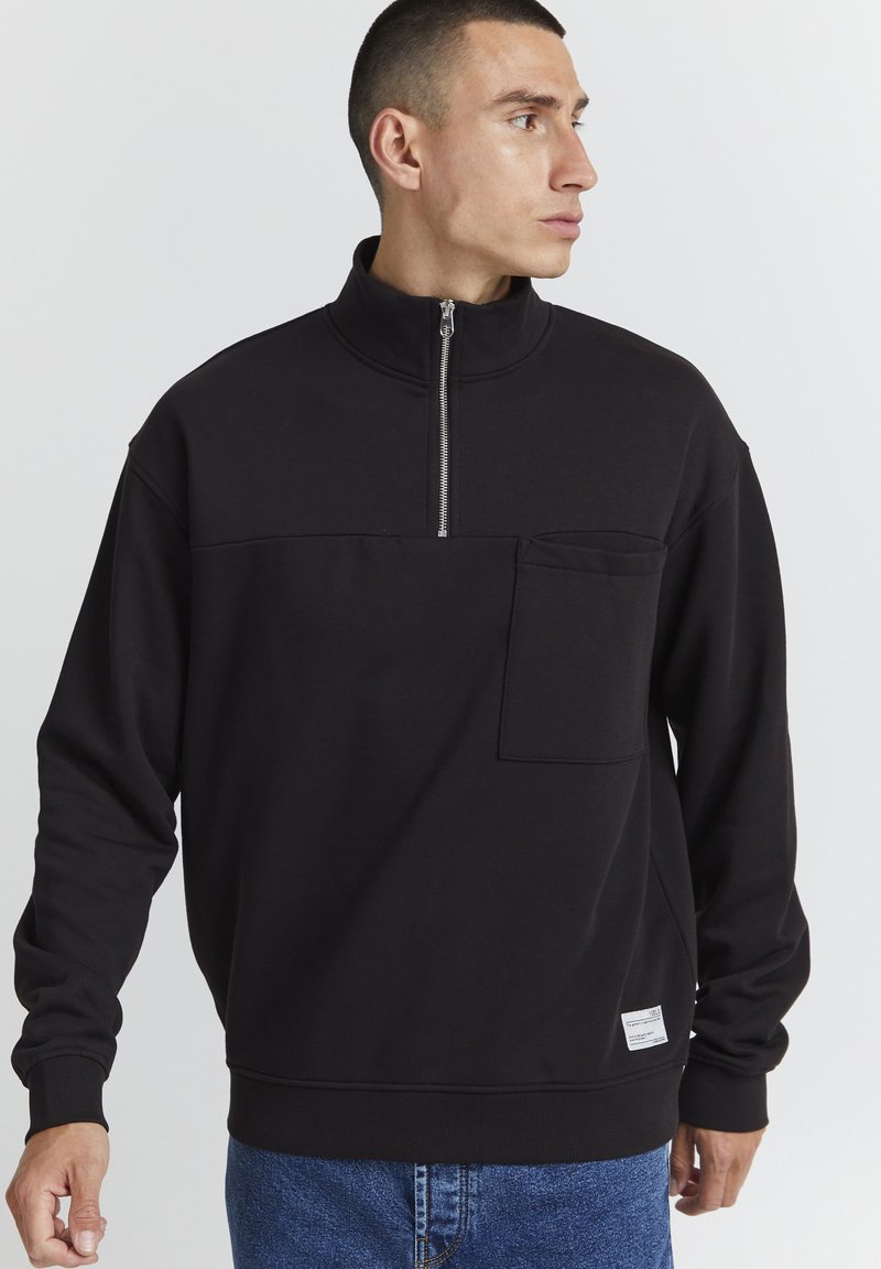 Sort zip-hals sweatshirts med en brystlomme, lavet af blødt stof, med lange ærmer og en afslappet pasform.