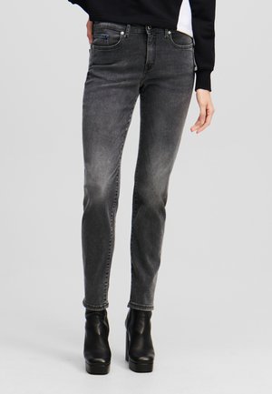 Gray denim skinny jeans with a mid-rise waist, front pockets, and subtle fading. Styled with black platform ankle boots.