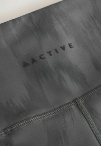 Black athletic wear featuring a textured fabric with a subtle pattern, stitched seams, and an embossed "ACTIVE" logo.