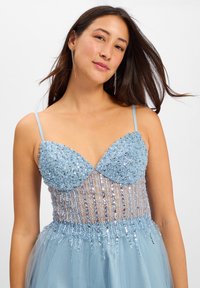 Abito azzurro chiaro con paillettes, dotato di un corpetto aderente, sovrapposizione trasparente e gonna in morbido tulle. Presenta spalline sottili e dettagli scintillanti.