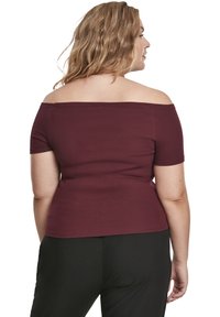 Burgundská top bez ramínek s ribbed designem a krátkými rukávy, vypasovaný, s hladkou texturou, v kombinaci s černými kalhotami.