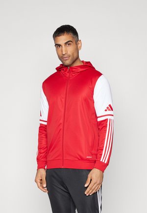 Red athletic jacket with a hood, white sleeves featuring three stripes, zip closure, and ribbed cuffs. Smooth texture, sport design.